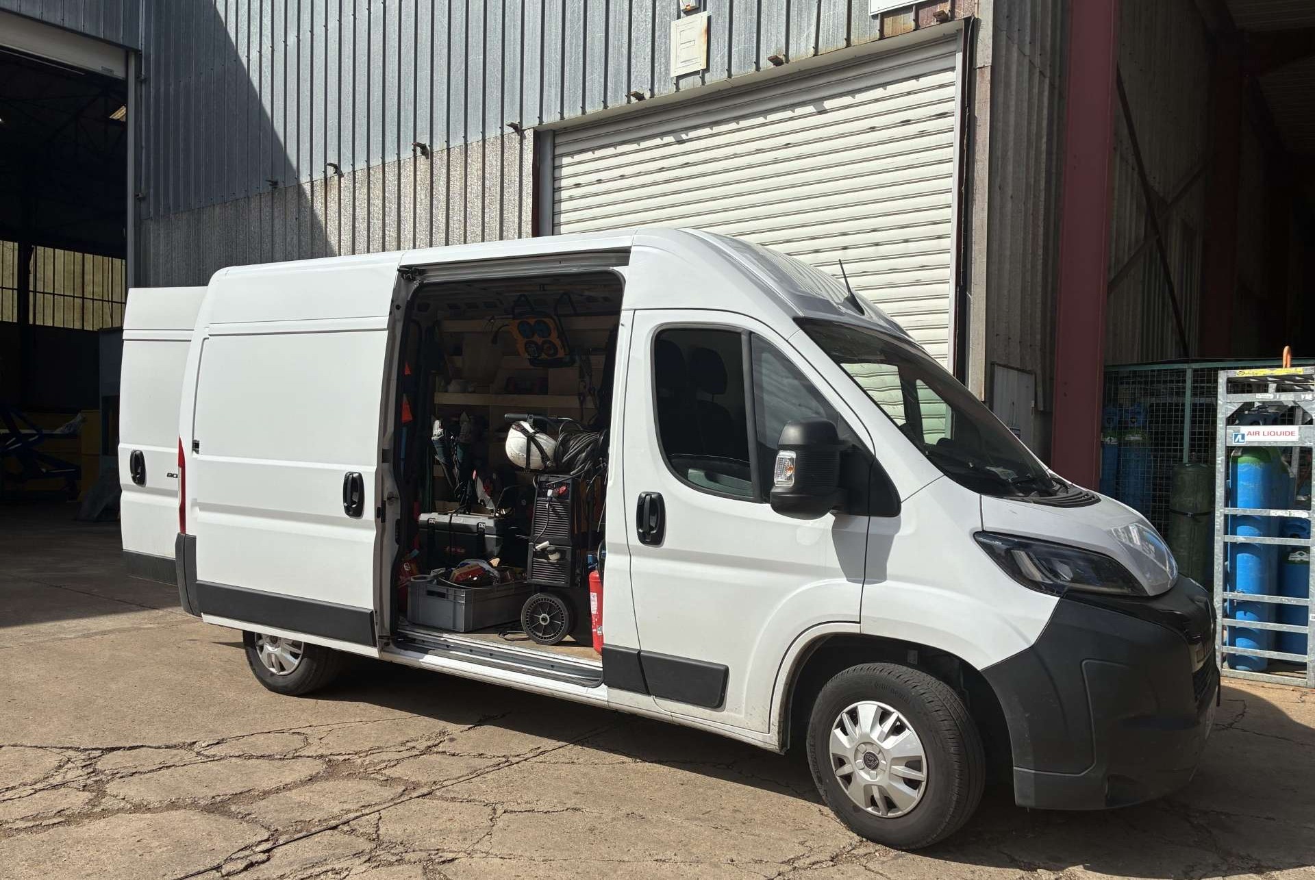 Camion-atelier blanc ALLIOSS porte latérale ouverte, équipé d’outillage et d’un poste de soudage
