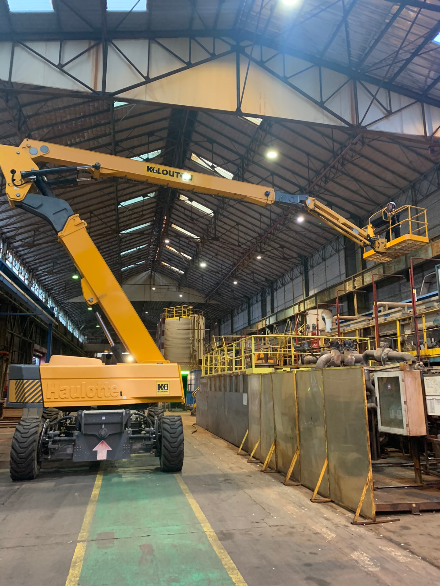 Nacelle télescopique jaune déployée dans un atelier industriel