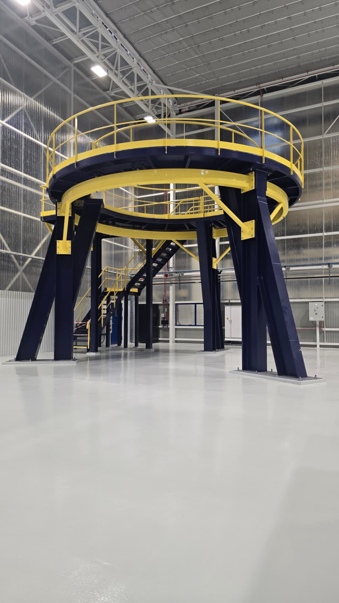 Station de montage bleu foncé avec passerelles et garde-corps jaunes installée sur site
